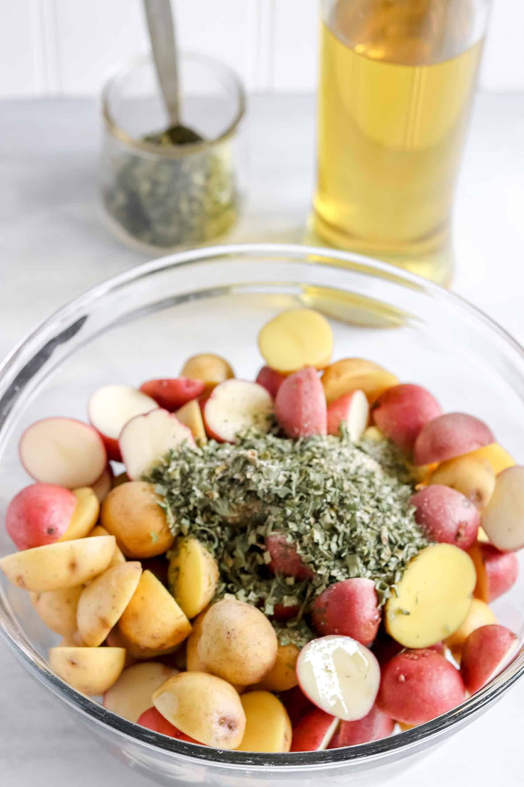 Bowl with Potatoes Ranch Seasoning. With Avocado Oil and Ranch Seasoning behind the bowl. https://www.atwistedplate.com/roasted-ranch-potatoes/