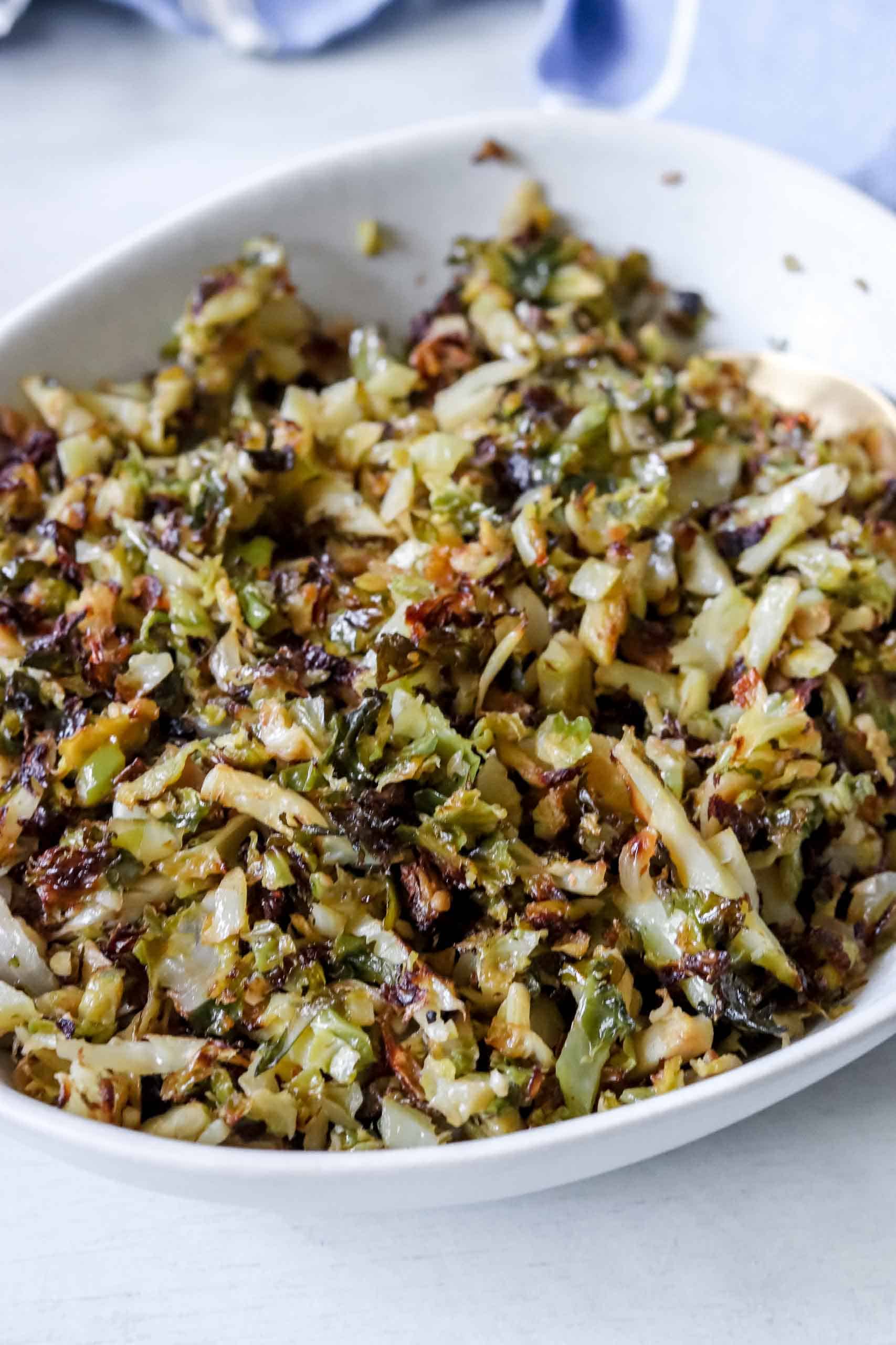 Close up of a bowl Garlic, Onion and Brussel sprouts. There is a blue towel with thin white stripes behind it. https://www.atwistedplate.com/garlic--onion-brussel-sprouts